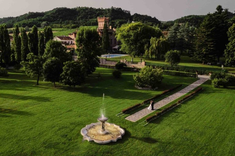 Vista aerea del Castello di Montegioco con gli sposi che camminano nel giardino. Location perfetta per un matrimonio romantico in Piemonte.