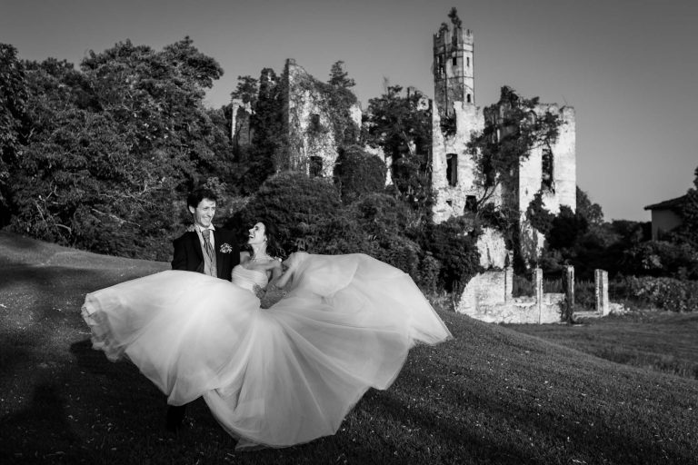 Sposi felici in posa davanti alle rovine della Tenuta Castello di Cerrione durante il loro matrimonio
